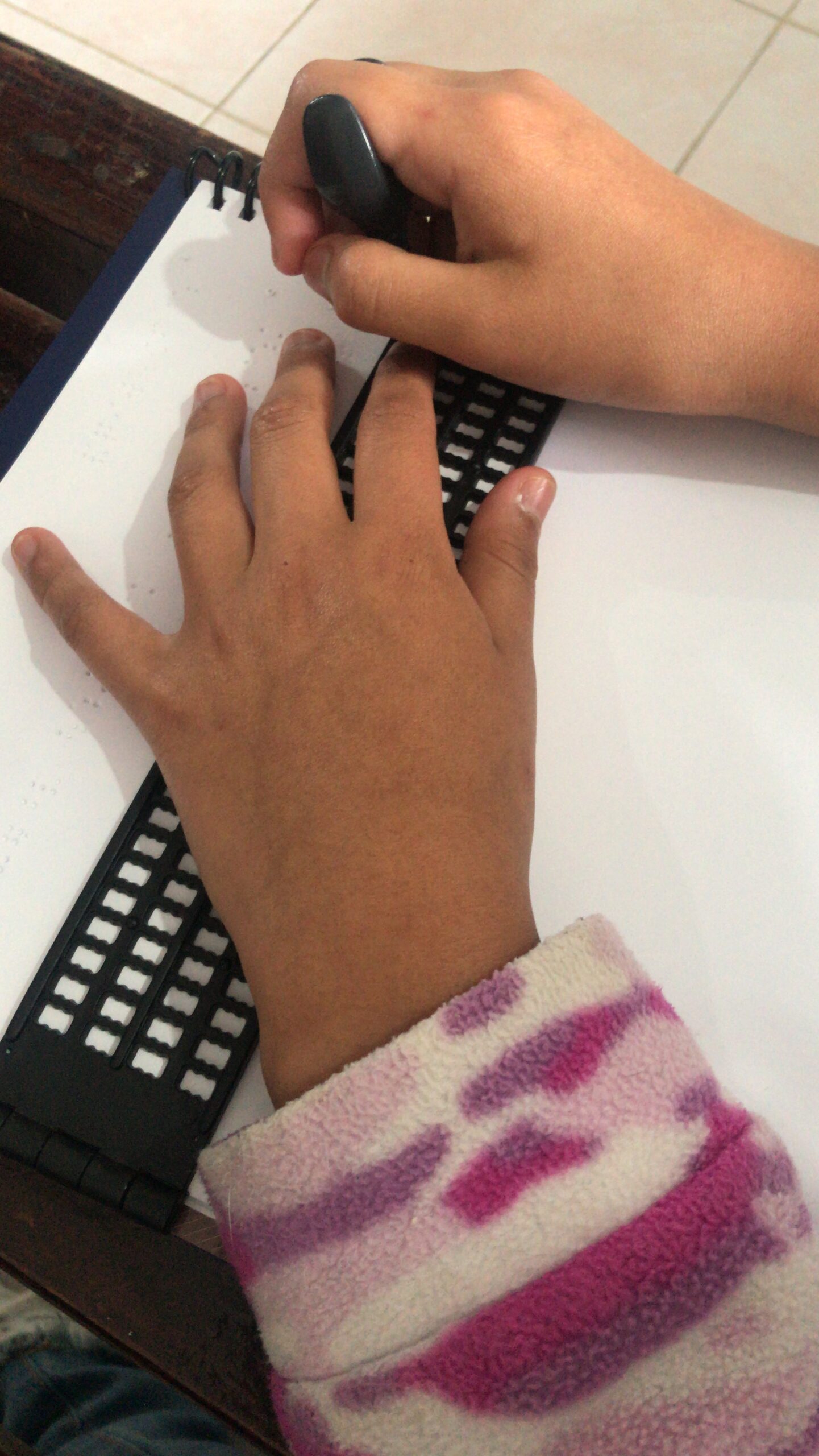 niña usando una regleta Braille